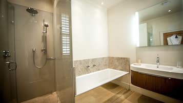 A modern bathroom with a glass-enclosed shower, a freestanding bathtub, and a vanity with a mirror.