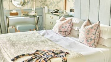 Una cama bien hecha con almohadillas estampadas, una colcha decorativa y una mesita de noche con lámpara.