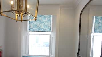 Quarto com um espelho grande, um sofá verde com textura, uma mesa de centro redonda de madeira e um candelabro.