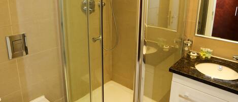 A modern bathroom with a glass-enclosed shower, a white toilet, and a vanity with a mirror.