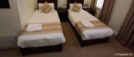 Een hotelkamer met twee bedden, elk met hoofdbord, nachtkastjes en lampen.