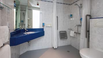 Un baño moderno con un lavabo azul, un inodoro y una zona de ducha.