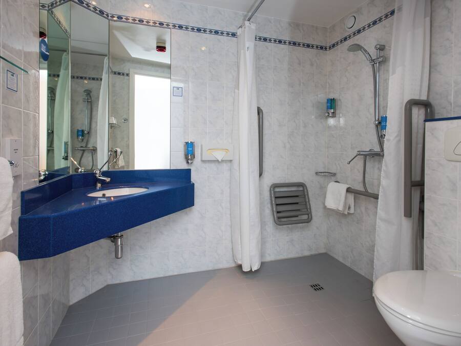 Un baño moderno con un lavabo azul, un inodoro y una zona de ducha.