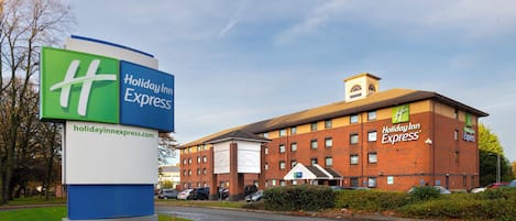 Un bâtiment de l’hôtel Holiday Inn Express, avec une enseigne bien visible, un espace de stationnement et un ciel dégagé.