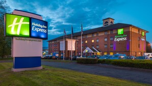 A Holiday Inn Express hotel with a large sign, multiple parking spaces, and a clear sky. - Holiday Inn Express Birmingham - Oldbury by IHG (Oldbury)