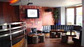 A modern lounge area with a curved bar, leather seating, and a large screen displaying the word "Sky". - Whites Hotel (Newcastle-upon-Tyne)