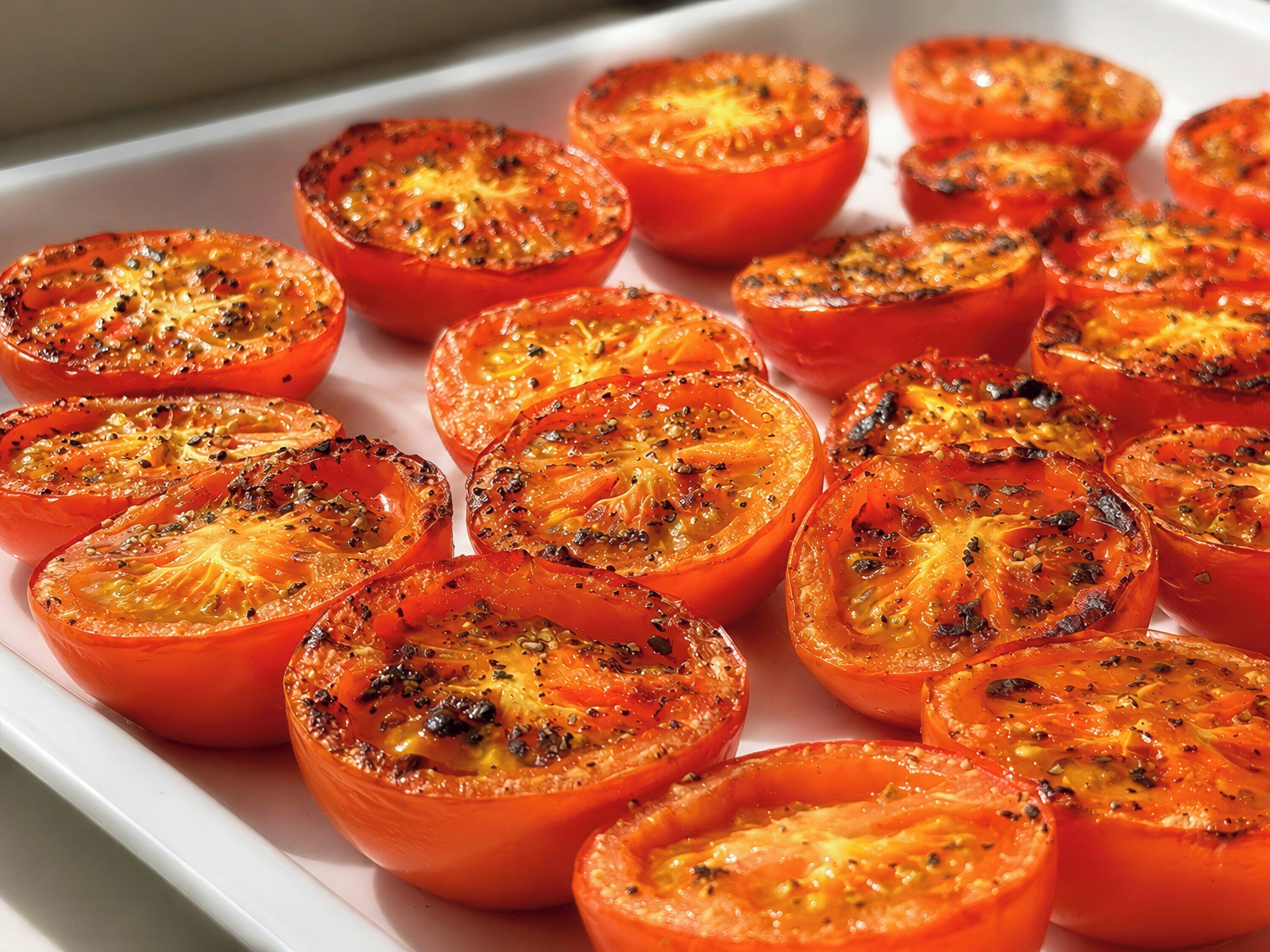 A tray of sliced tomatoes with herbs.