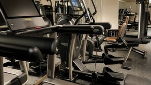 Un gimnasio con diferentes máquinas de ejercicio, incluyendo cintas de correr y bancos de pesas.