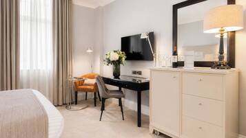 A hotel room with a bed, a desk, a chair, a television, a mirror, and a cabinet.