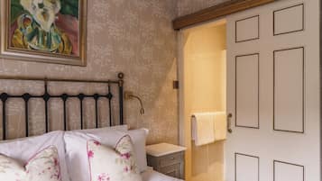 Um quarto com uma cama, mesa de cabeceira, quadro e porta.