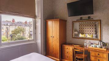 Ein Hotelzimmer mit großem Kleiderschrank, Schreibtisch mit Stuhl, Spiegel und Wandfernseher.