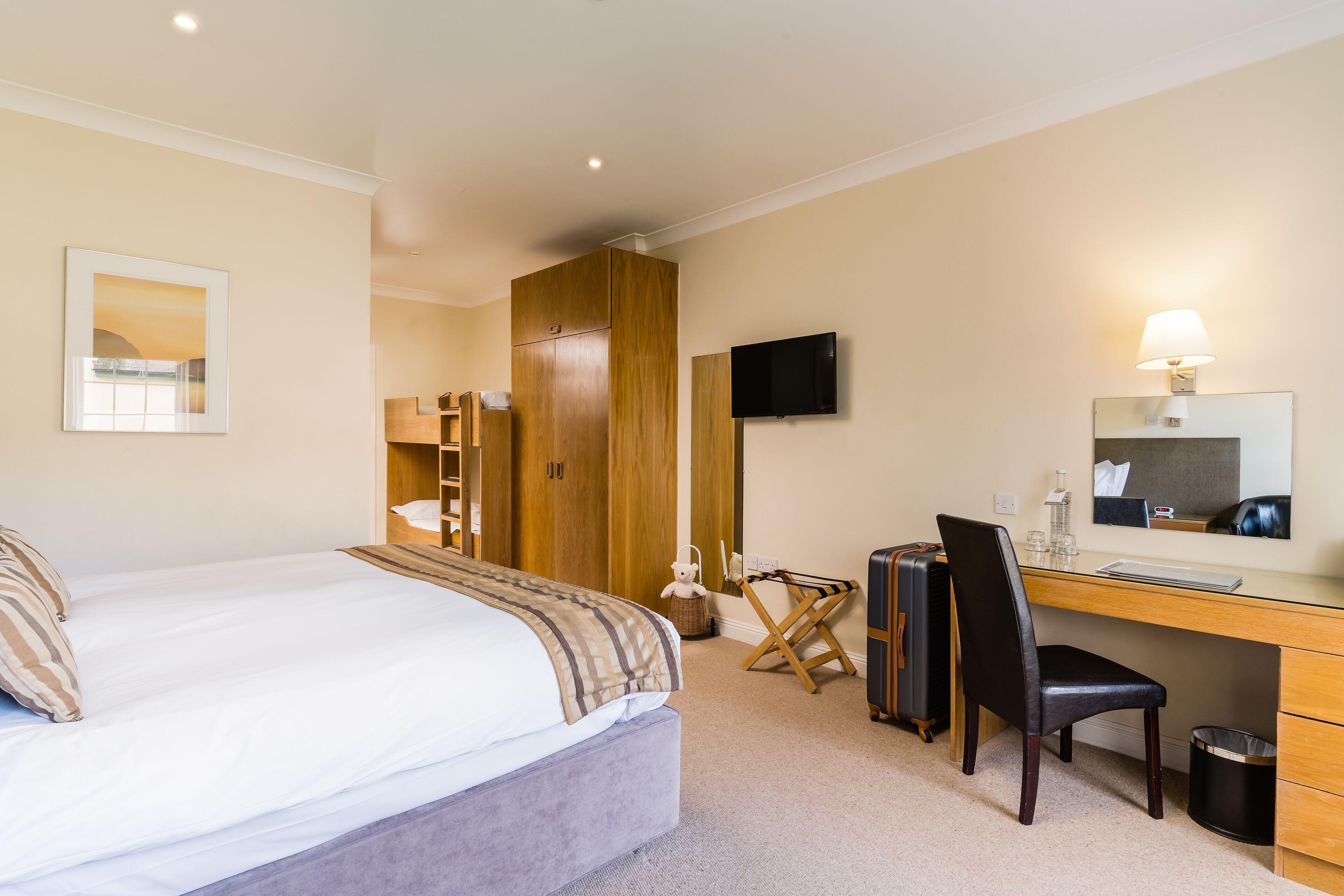 Habitación de hotel con cama, escritorio, silla y televisor.