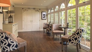 A spacious room with a large window, a door, and a table with chairs. - Forest Lodge (Lyndhurst)
