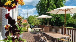 A wooden deck with outdoor furniture, including a table and chairs, and two white umbrellas. - Forest Lodge (Lyndhurst)