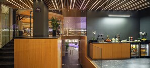 Un moderno vestíbulo de hotel con mostrador de recepción, zona de estar y una escalera.