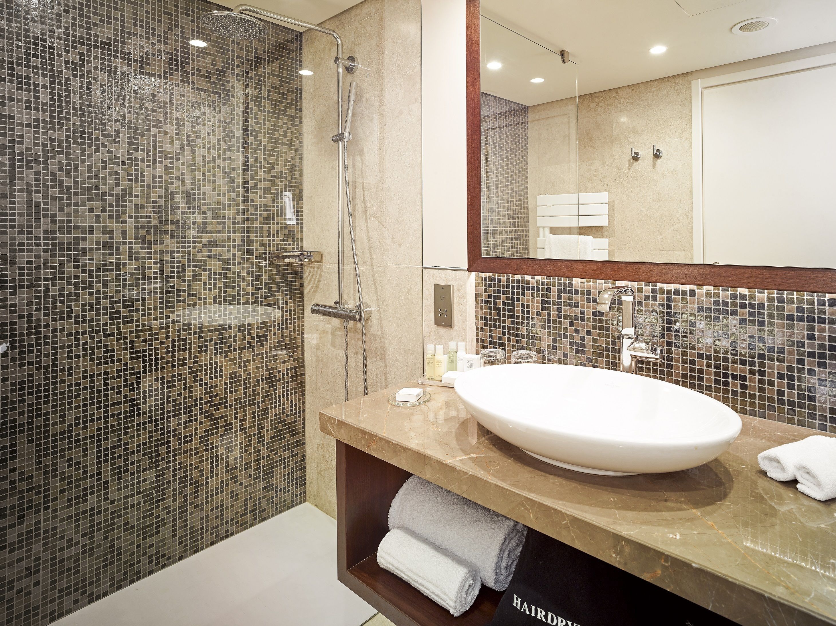 A modern bathroom with a glass-enclosed shower, a large sink, and a mirror above it.