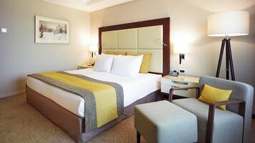 A hotel room with a bed, bedside table, lamp, chair, and a framed picture on the wall.