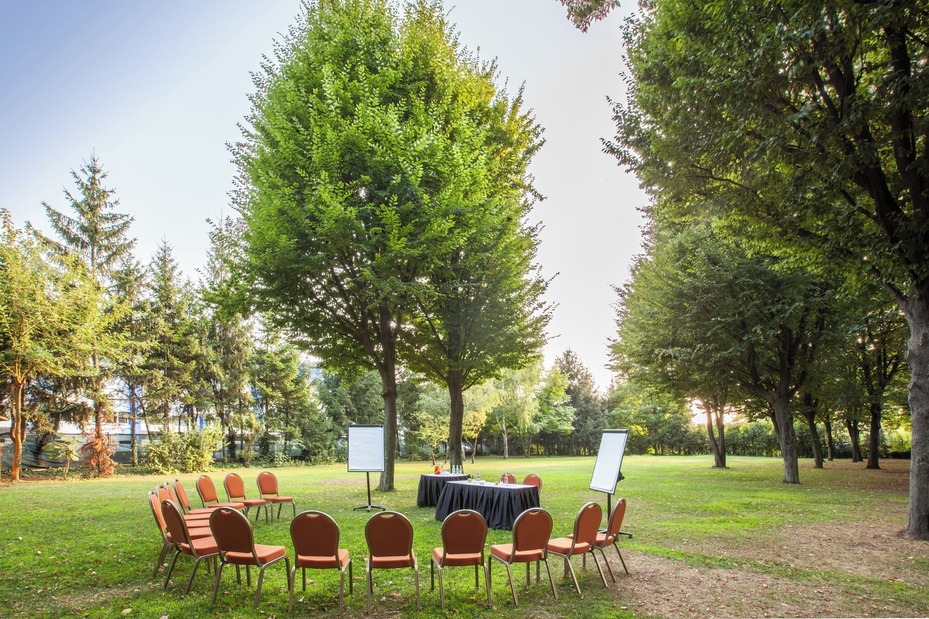 An outdoor event space with a round table, chairs, and a whiteboard.