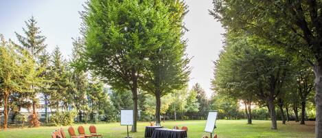 An outdoor event space with a round table, chairs, and a whiteboard.