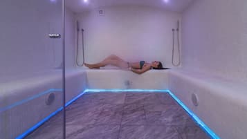 Una persona recostada en un jacuzzi con piso de baldosas e iluminación azul.