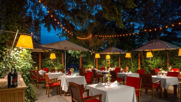 An outdoor dining area with tables and chairs, string lights, and umbrellas. - Crowne Plaza Bucharest by IHG (Bucharest)