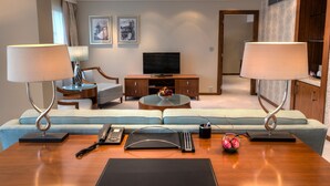 A modern hotel room with a sofa set, a television, a coffee table, and two lamps. - Crowne Plaza Bucharest by IHG (Bucharest)