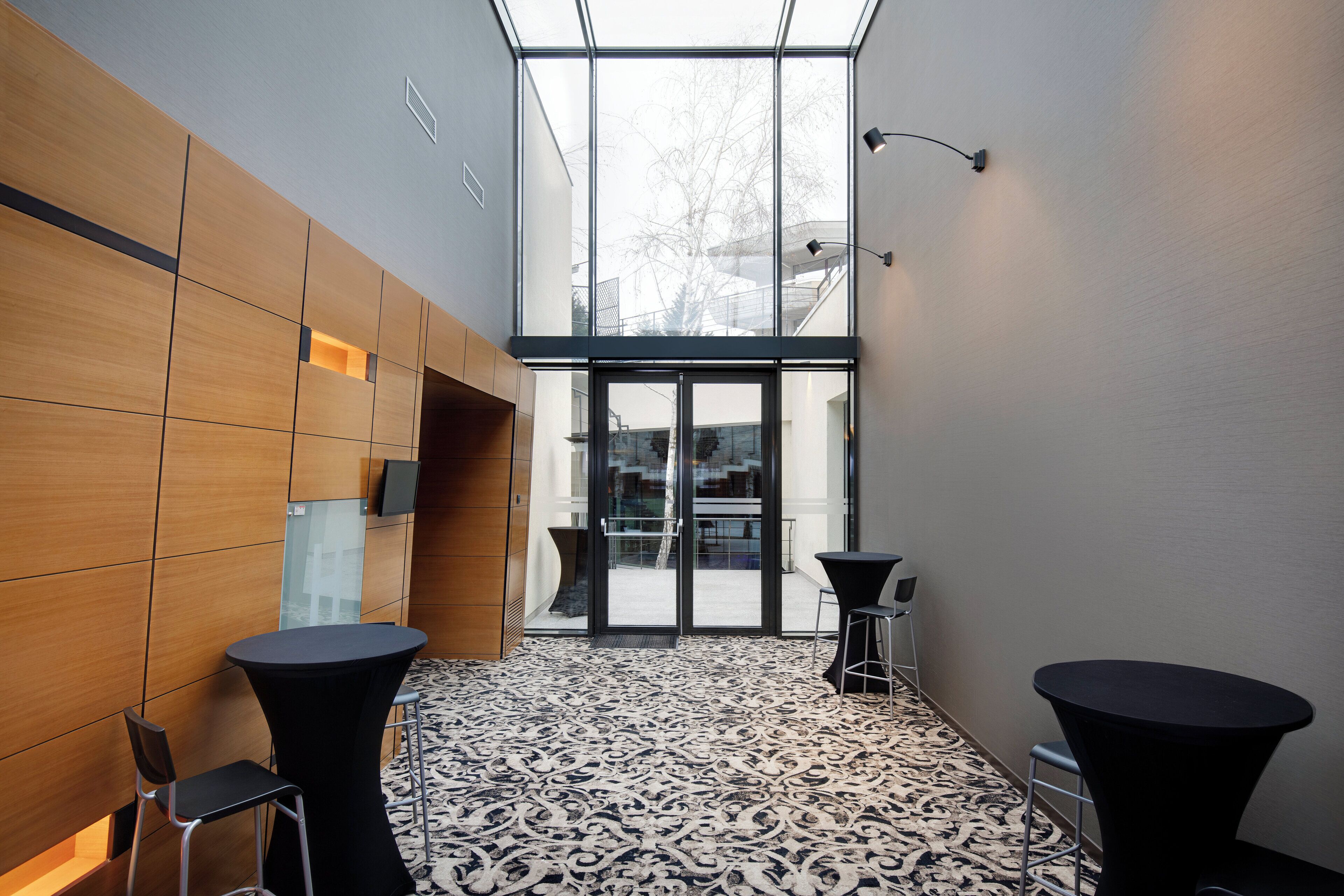 Interior moderno com balcão de recepção, dois banquetes e piso estampado.