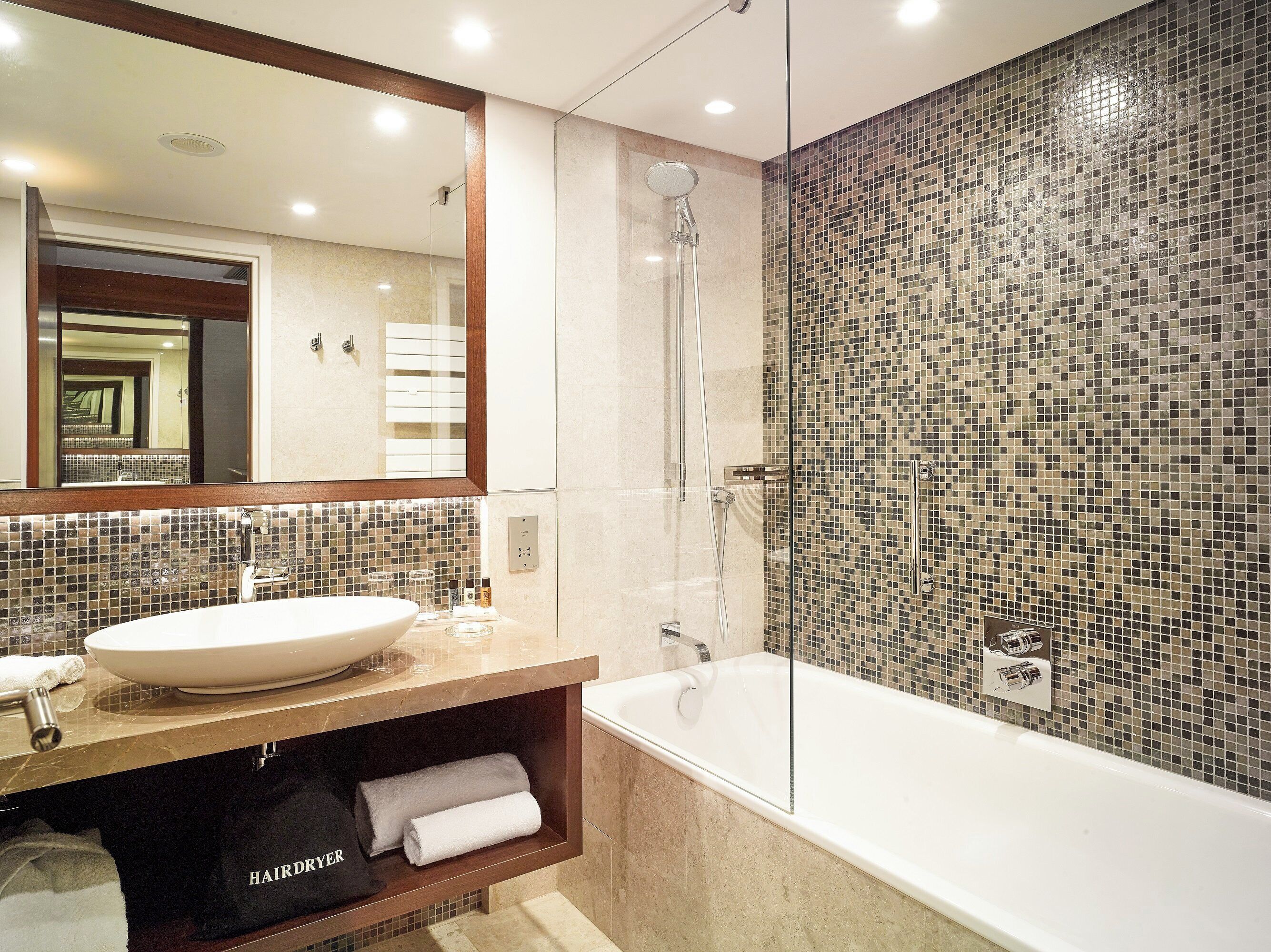A modern bathroom with a large mirror, a bathtub, and a shower enclosure.