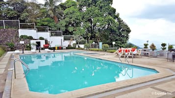 Relax by the serene pool surrounded by lush greenery and a stone wall.