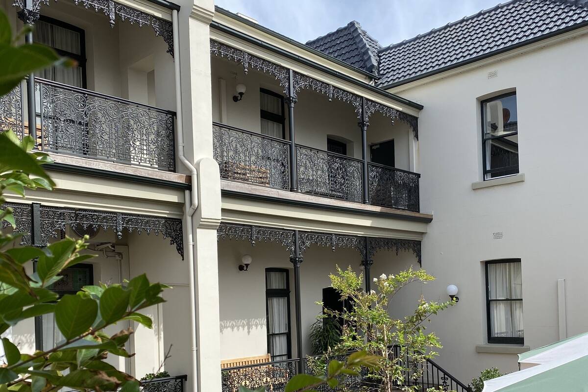 A multi-story building with balconies, outdoor seating, and potted plants.