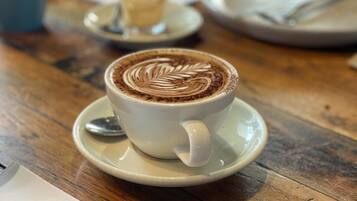 Una taza de café con decoración de arte latte sobre una mesa de madera.