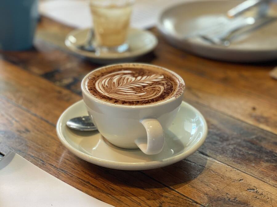 Una taza de café con decoración de arte latte sobre una mesa de madera.
