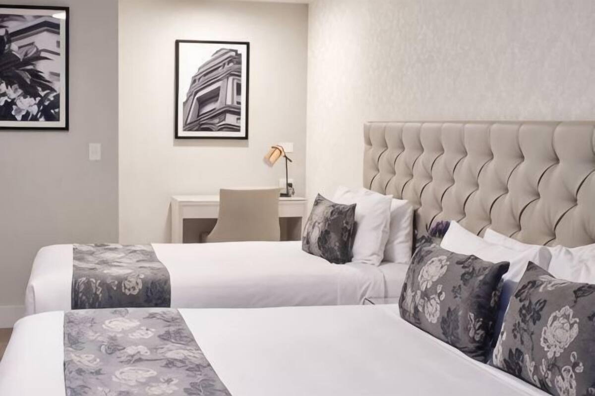 A hotel room with two beds, a desk, and a chair.