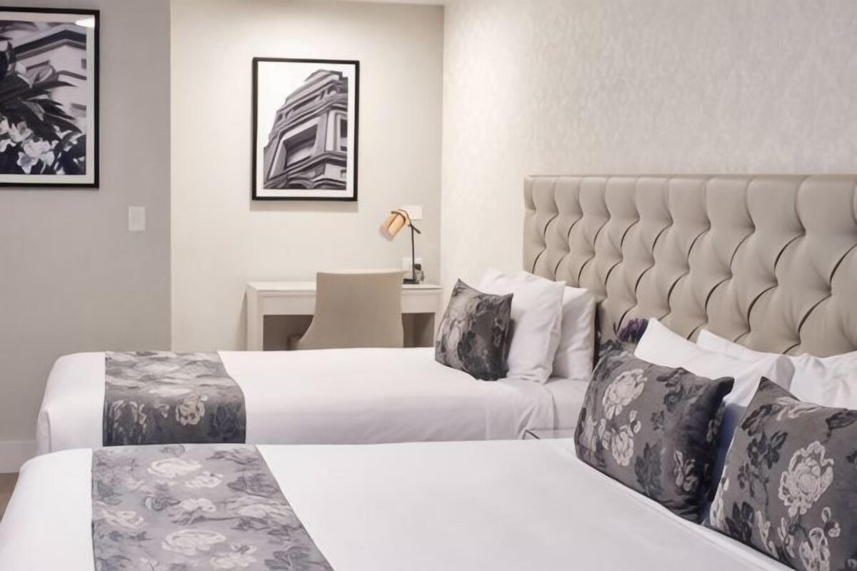 A hotel room with two beds, a desk, and a chair.