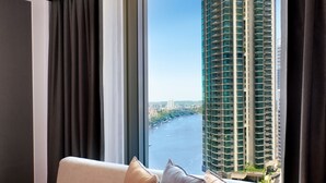 A modern living room with a sofa and a view of a river and tall buildings. - Brisbane Marriott Hotel (Brisbane)