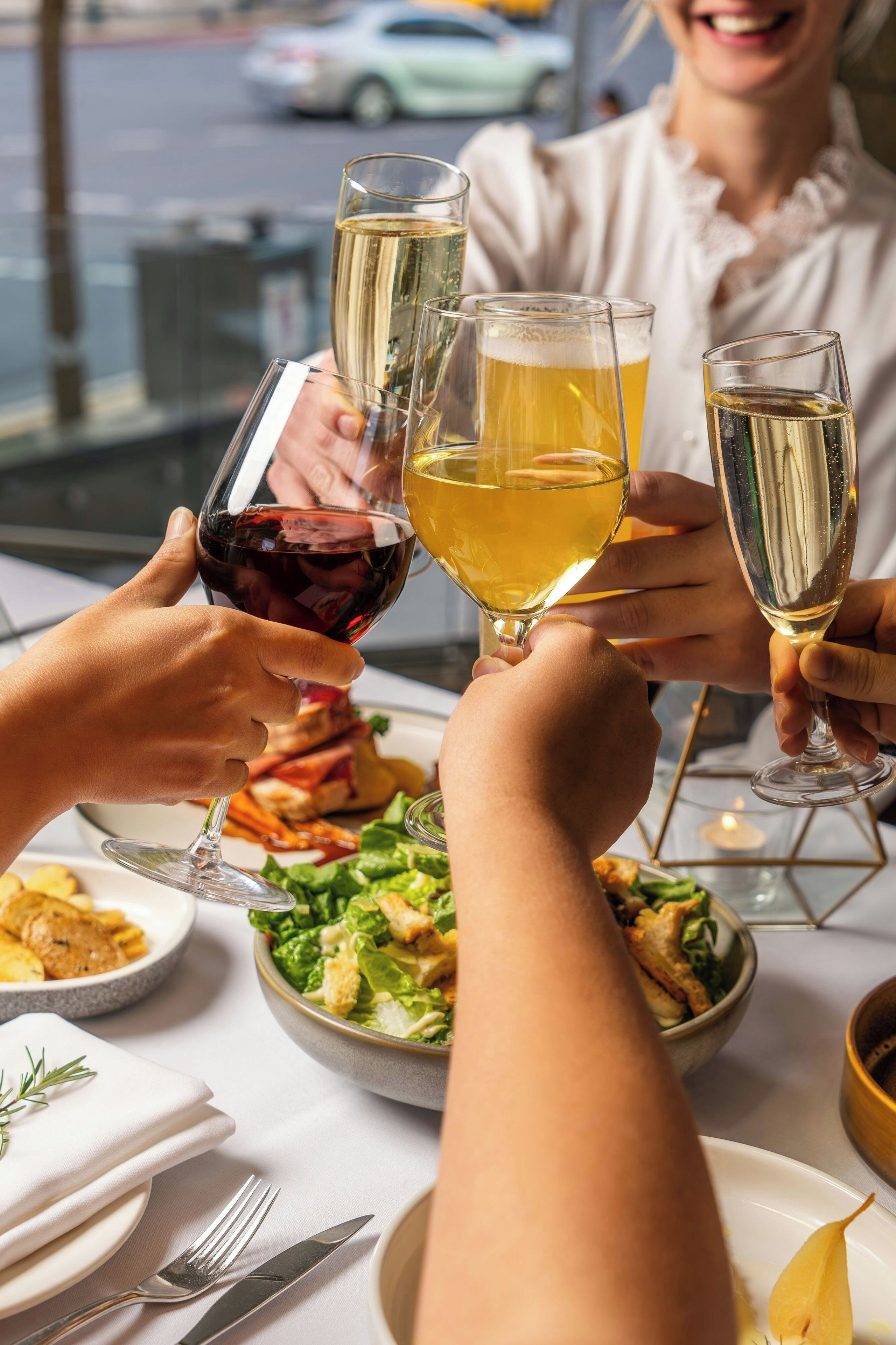A group of people toasting with wine glasses at a table with a meal.