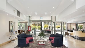 A modern lobby with a reception desk, seating area, and a view of the street. - Melbourne Metropole Central (Fitzroy)