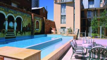 A swimming pool with lounge chairs and a mural on the adjacent building.