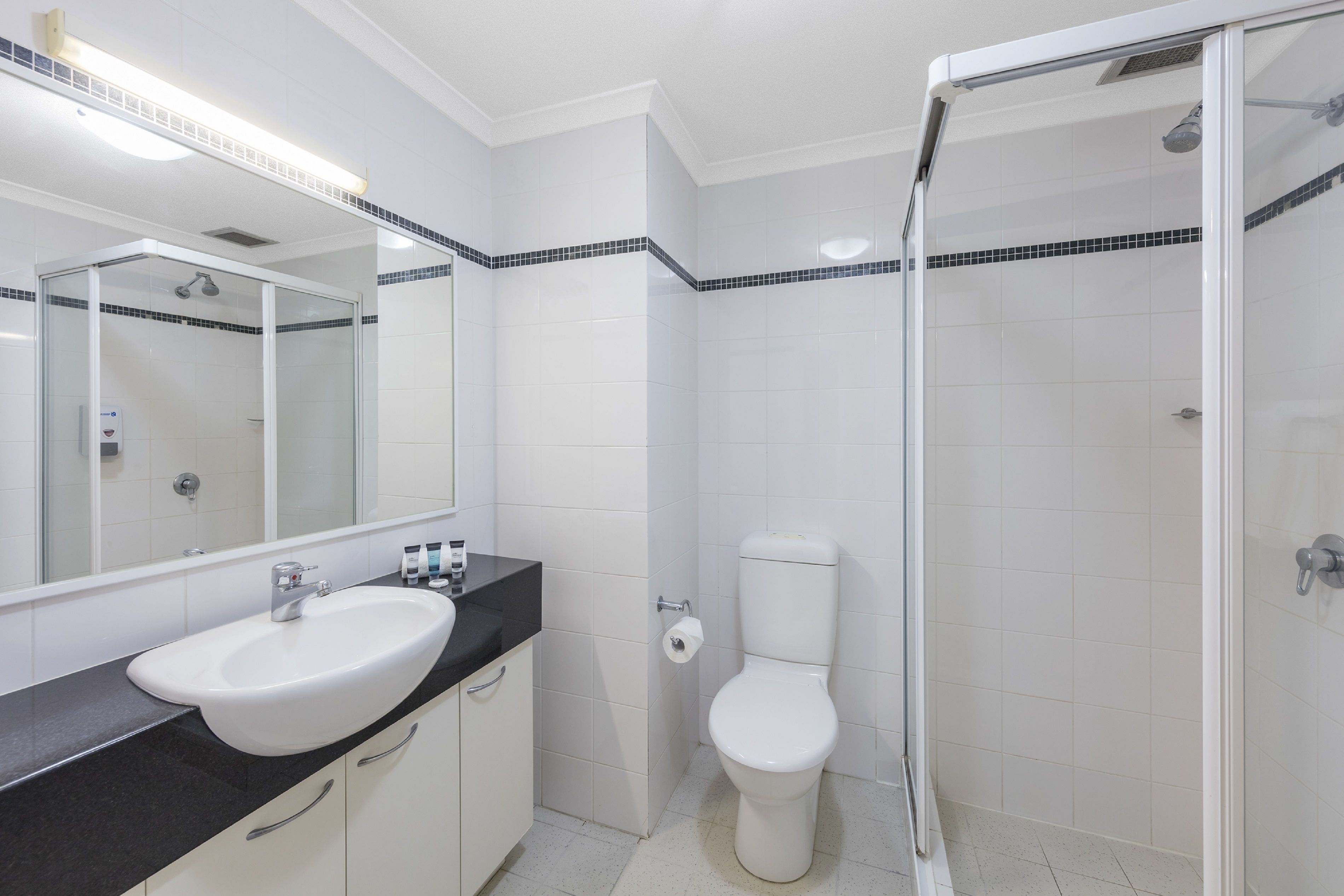 Een badkamer met een wit wastafelmeubel, toilet en douchecabine.