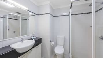 A bathroom with a white sink, toilet, and glass-enclosed shower.