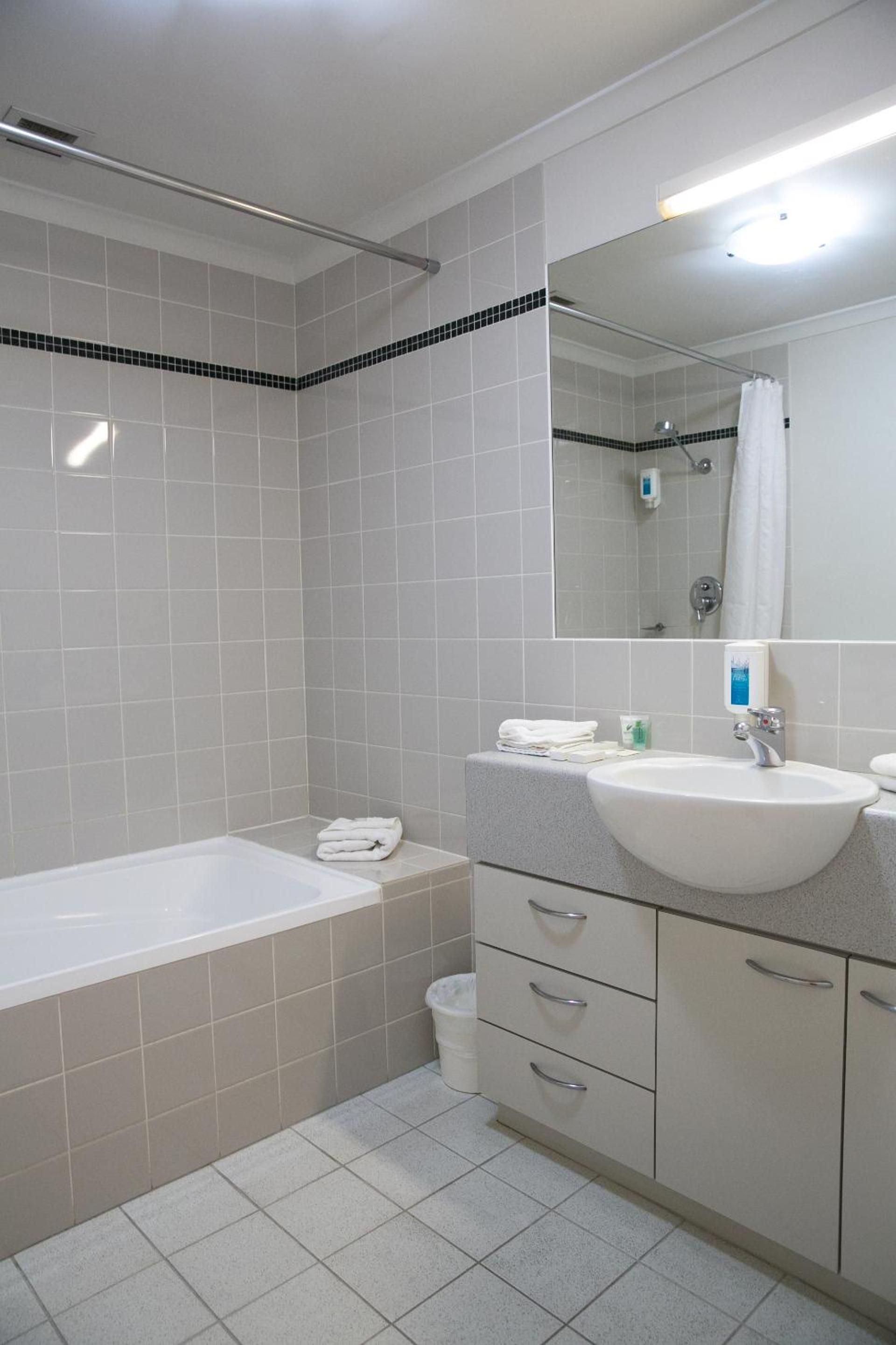 Ein Badezimmer mit einer Badewanne, einem Waschbecken, einem Spiegel und einer Dusche.