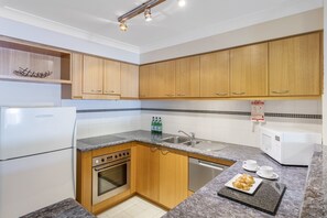 A compact kitchen with wooden cabinets, a built-in oven, a microwave, and a sink.