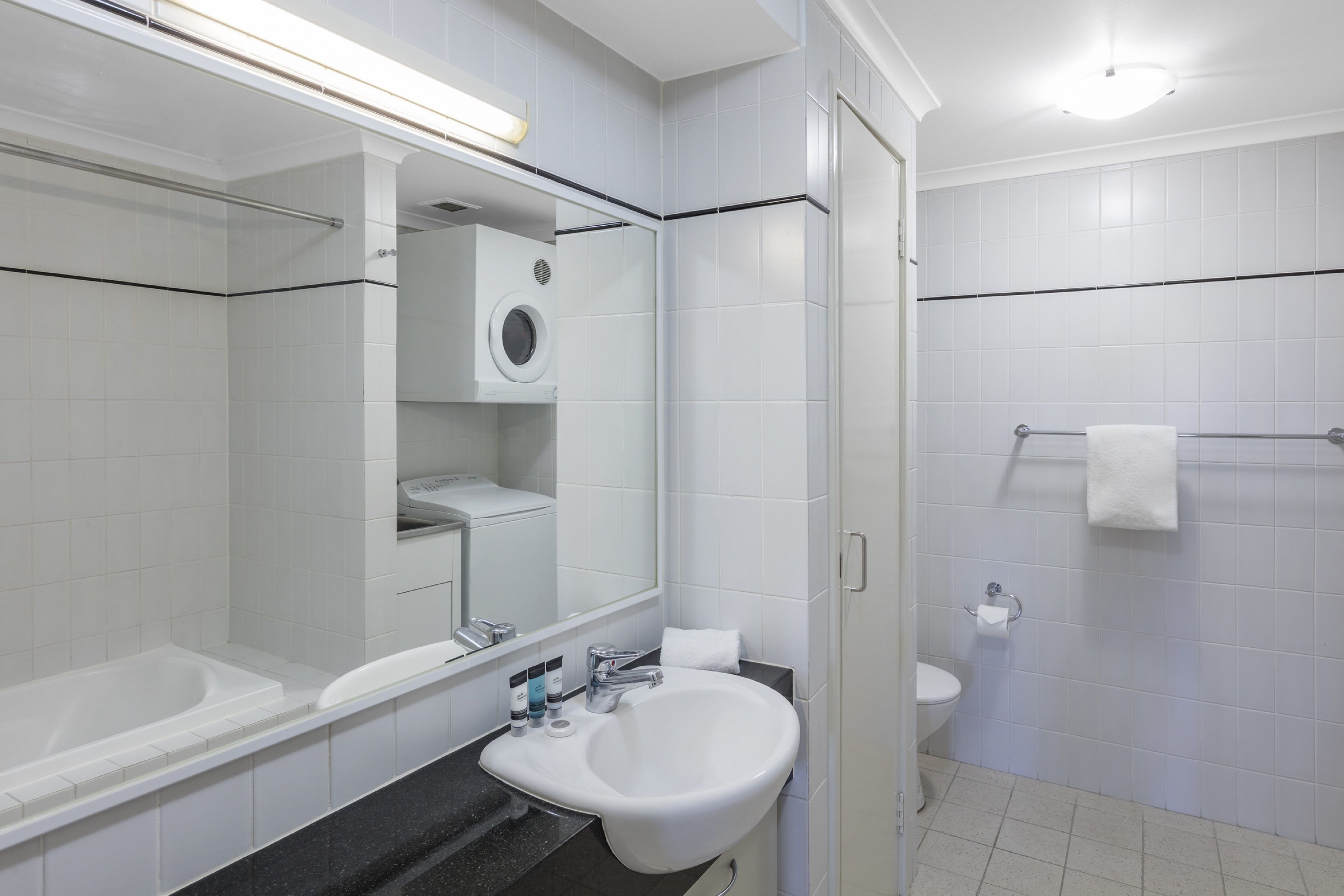 Un bagno moderno con lavandino, specchio e water bianchi.