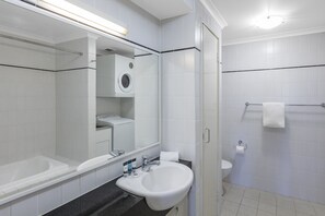 A modern bathroom with a white sink, mirror, and toilet.
