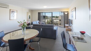 A modern hotel room with a dining area, a sofa, and a TV. - Nesuto Mounts Bay (Perth)