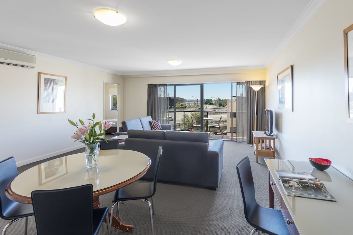 A modern hotel room with a dining area, a sofa, and a TV.