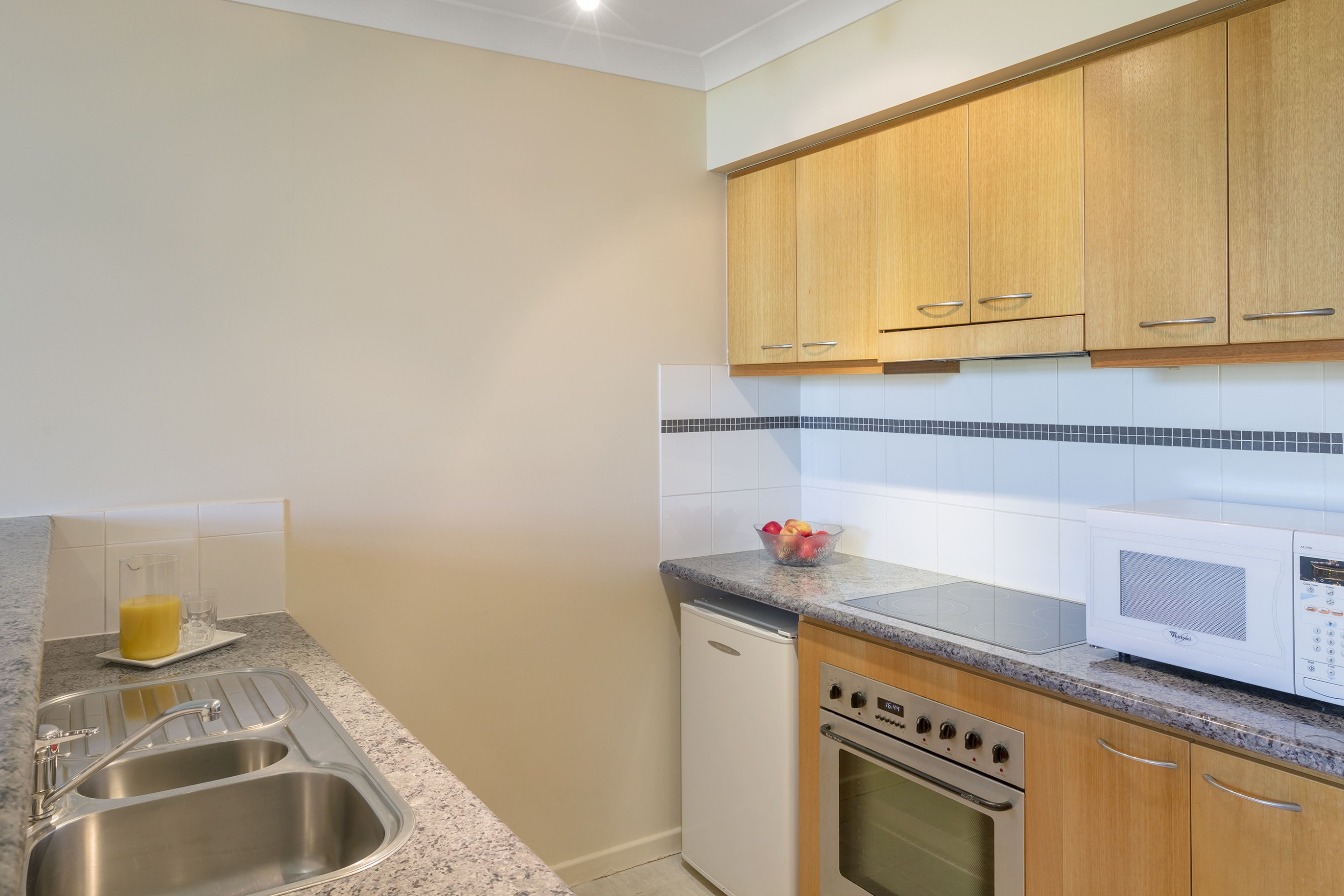 A kitchen with a stainless steel sink, a microwave, a dishwasher, and wooden cabinets.