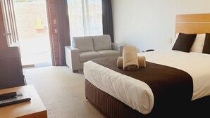 A hotel room with a bed, a chair, a desk, and a window. - Golden Reef Motor Inn (Strathdale)