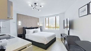 A modern hotel room with a bed, a desk, a chair, a TV, and a large window. - Whistler Cascade Lodge (Whistler)