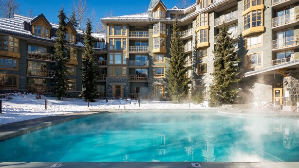 A large indoor pool with clear water, surrounded by a multi-story building with balconies and large windows. - Whistler Cascade Lodge (Whistler)